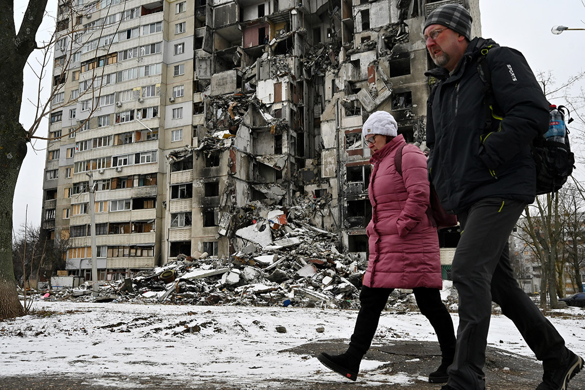 A man and a woman walk past an apartment block