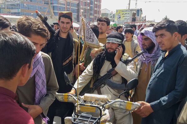 A Taliban fighter (centre) surrounded by locals at Pul-e-Khumri, the capital of Afghanistan's northern Baghlan Province, on 11 August. The city, located about 200 km north of Kabul, is one of ten Afghan provincial centres captured by the Taliban since 6 August. (AFP via Getty Images)