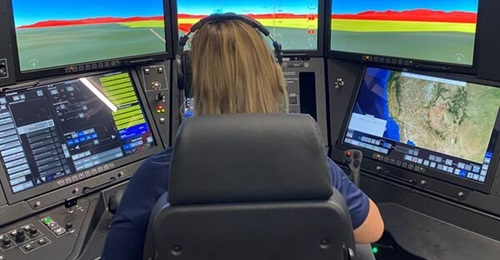 A GA-ASI technician showcases the MQ-9B SkyGuardian Mission Trainer, with CAE Prodigy-generated images on the screen.