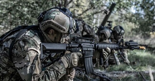 A Swedish soldier equipped with Saab Gamer simulation devices including a laser detector device on the helmet and laser transmitter on the weapon barrel behind the blank firing attachment.