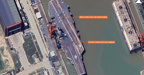 Satellite imagery showing CV 18 
        
        at Jiangnan Changxingdao Shipyard in Shanghai. Markings on the deck are indicative of fixed-wing aircraft activity during sea trials.