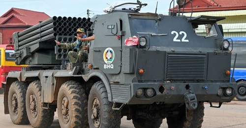 Cambodian soldiers gesture while standing on a truck carrying a Russian-made BM-21 rocket launcher travelling along a street in Oddar Meanchey province on 25 July 2025.