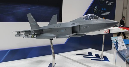 A KAI KF-21 model with underslung air-to-air missiles, drop tanks, and smart air-to-ground bombs is displayed at DSEI Japan 2025.