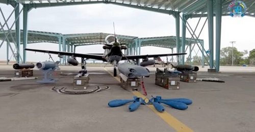An A-29 displayed with its weapons, including an SUU-20 pod for launching the training bombs in front of it.