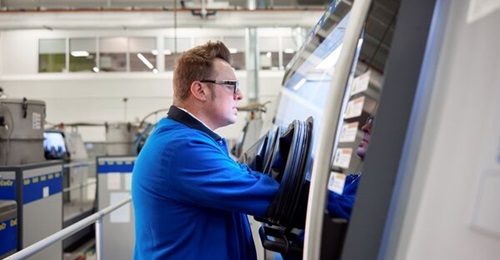 An operator uses a Colibrium Additive M2 laser powder bed fusion machine at the GE Aerospace Additive Technology Center in Cincinnati, Ohio. Divergent Technologies employs laser powder bed fusion as part of its advanced manufacturing system.