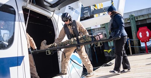Personnel demonstrate the transfer of a simulated casualty from a seaglider to a dock during a rescue demonstration for the US Marine Corps.