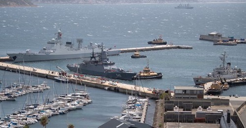 in Simon's Town naval base on the left, with tugs helping 
        
         to dock in the centre, 
        
         on the right, and Taihu anchored in the background.