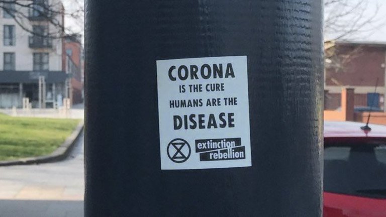 An image of a fake Extinction Rebellion sticker with a message on the Covid-19 pandemic that conveys eco-fascist themes, that was posted by a now-suspended Twitter account. The stickers were left on lampposts in Bedford and Brighton. (Twitter)