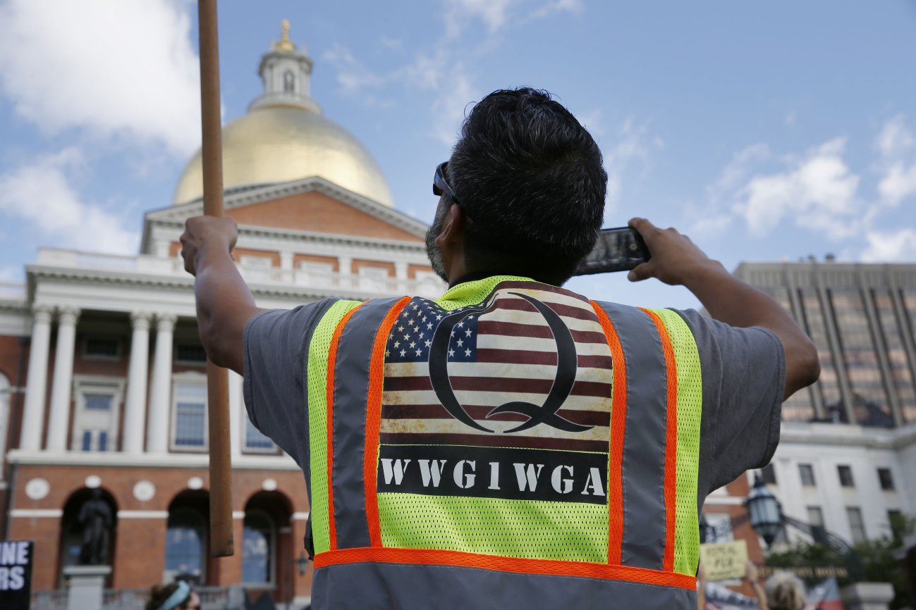 A demonstrator wearing a QAnon vest attends a ‘No Mandatory Flu Shot’ rally outside the State House in Boston, Massachusetts, on 30 August 2020. The acronym on his bib, WWG1WGA, is a common QAnon rallying cry, meaning ‘Where We Go One, We Go All’. (Jessica Rinaldi/The Boston Globe via Getty Images)