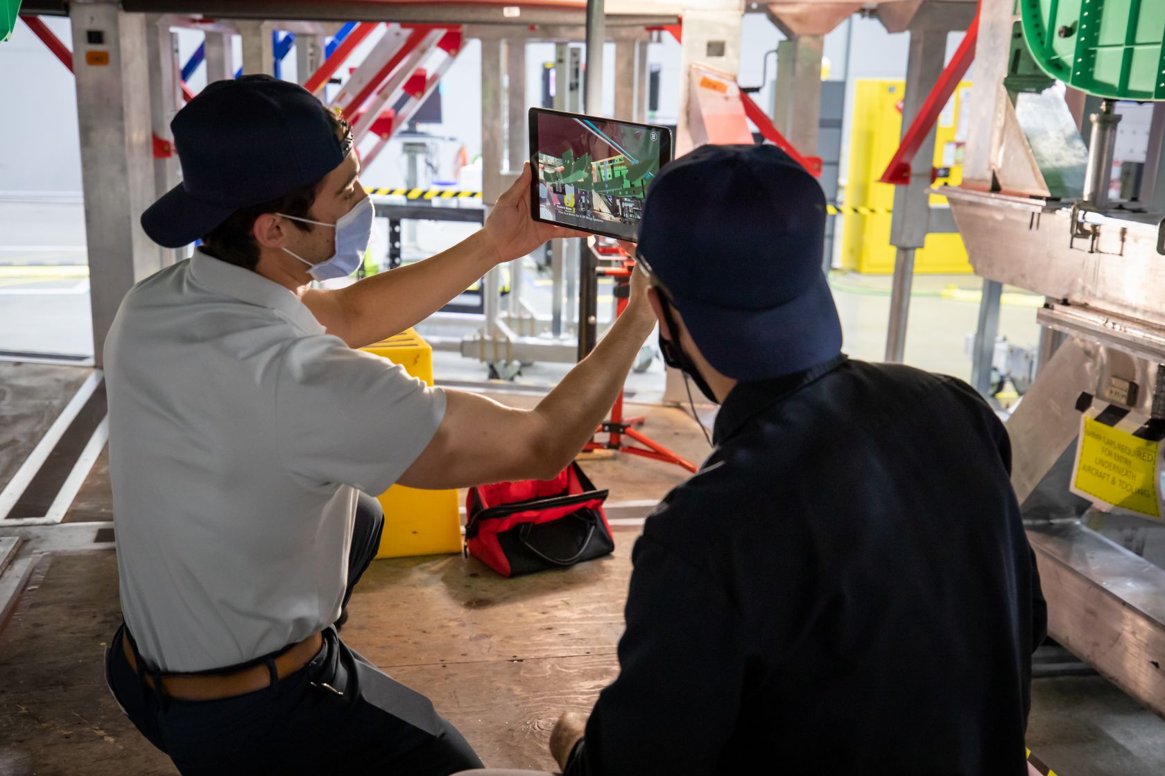 Two employees leverage augmented reality and 3D work instructions to build an air vehicle. While not demonstrative of the full scope of a digital thread (such as connecting engineering, manufacturing, and the supply chain in one virtual environment for a single source of truth), it visually connotes how a company can apply that data model in action on the shop floor. (Lockheed Martin)